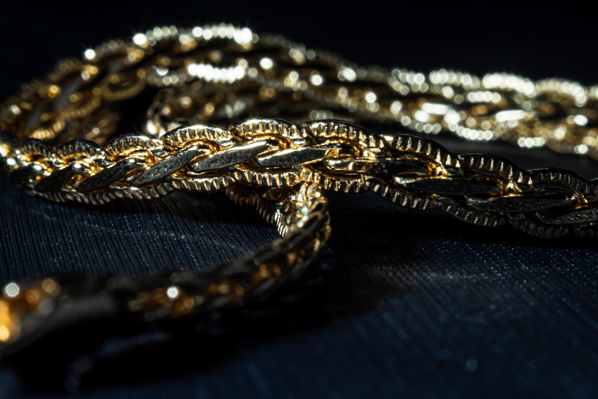 Imagen de una cadena de oro con el fondo negro.